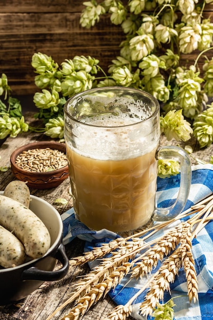 Ensemble d'Oktoberfest. Bière non filtrée, weisswurst, épillets de céréales, houblon. Cuisine allemande traditionnelle, nourriture de festival. Tasse, serviette en lin, fond en béton de pierre, place pour le texte