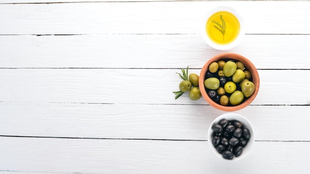 Un ensemble d'olives et d'huile d'olive et de romarin Olives vertes et olives noires Sur un fond en bois blanc Espace libre pour le texte