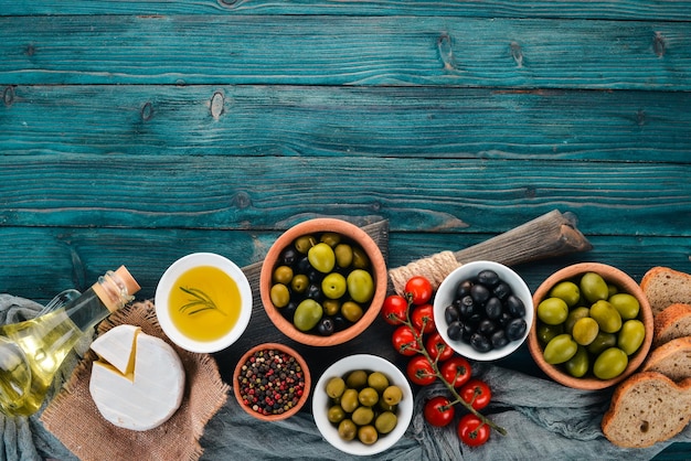 Un ensemble d'olives vertes et d'olives noires et de collations Sur une table en bois bleue Espace libre pour le texte