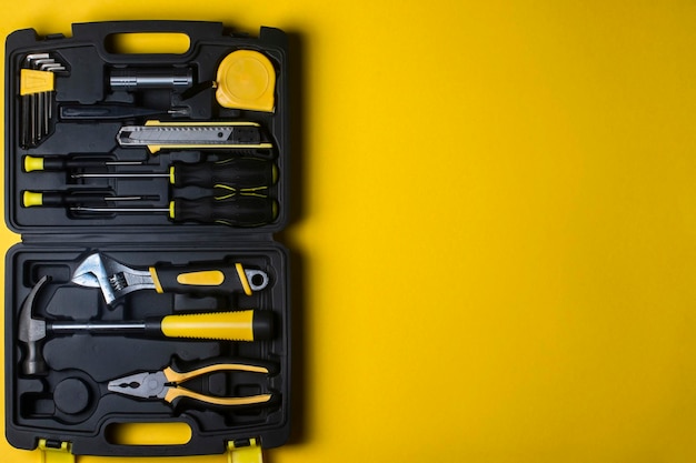 Un ensemble d'outils à main dans une boîte en plastique sur fond jaune.