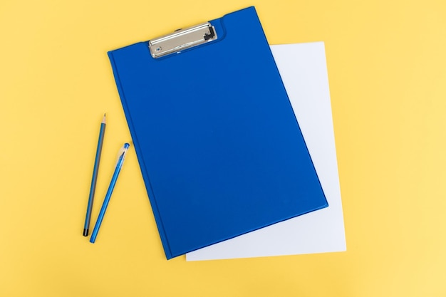 Un ensemble de papeterie bleue comme un modèle avec un endroit pour copier sur une table jaune un stylo un dossier