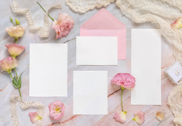 Ensemble de papeterie de mariage avec enveloppe posée sur une table en marbre décorée de fleurs et de rubans