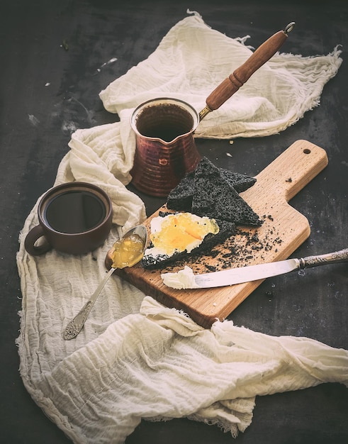 Ensemble de petit-déjeuner Coffe toasts noirs avec fromage à la crème et marmelade d'orange sur la surface de la table de grunge sombre