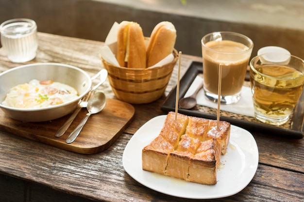 Ensemble de petit déjeuner, pain, café chaud, omelette aux œufs et thé chaud sur une table en bois, lumière naturelle