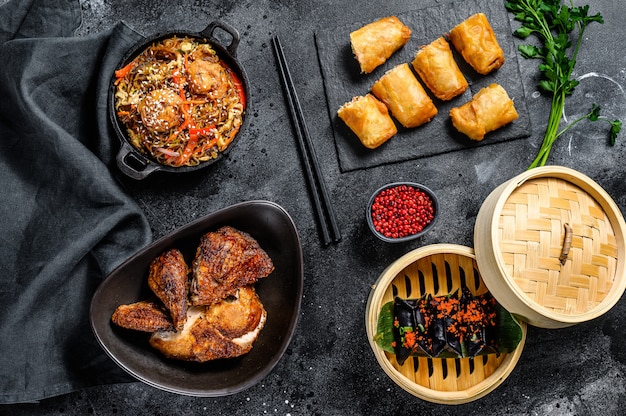 Ensemble de plats de cuisine chinoise, fond noir de nourriture. Nouilles chinoises, boulettes, canard laqué, dim sum, rouleaux de printemps. Célèbre. Vue de dessus