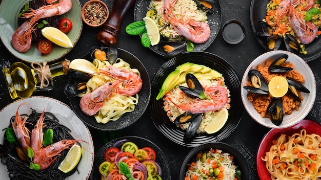 Un ensemble de plats de fruits de mer sur fond noir Couscous de riz au boulgour Pâtes Vue de dessus Espace libre pour votre texte