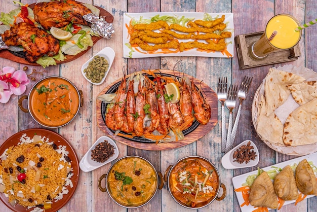 Ensemble de plats indiens boeuf samoussas crevette poulet tikka tikka masala korma kashmiri riz pilaf naan ail mangue lassi