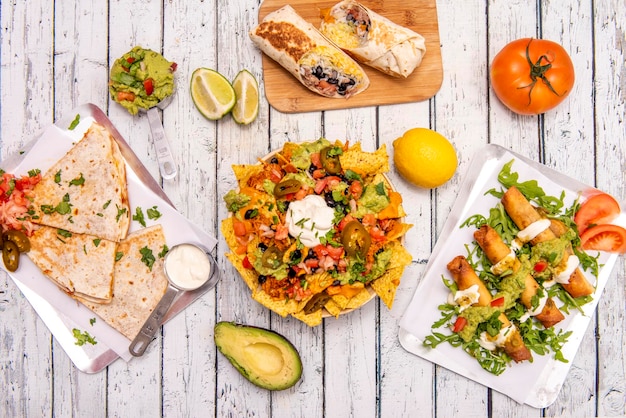 Ensemble de plats mexicains populaires avec nachos et burritos guacamole avec quesadillas de riz et tacos dorés sur tableau blanc