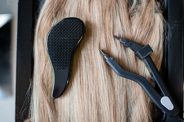 Photo un ensemble de plusieurs outils d'extension de cheveux pour une femme blonde dans un salon de beauté pinces et micro tubes