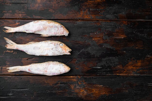 Ensemble de poissons surmullet congelés, sur fond de table en bois foncé ancien, vue de dessus à plat, avec espace de copie pour le texte