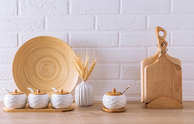 Un ensemble de pots de rangement en céramique blanche et de planches à découper en bois à l'intérieur d'une cuisine écologique minimalisme Articles écologiques