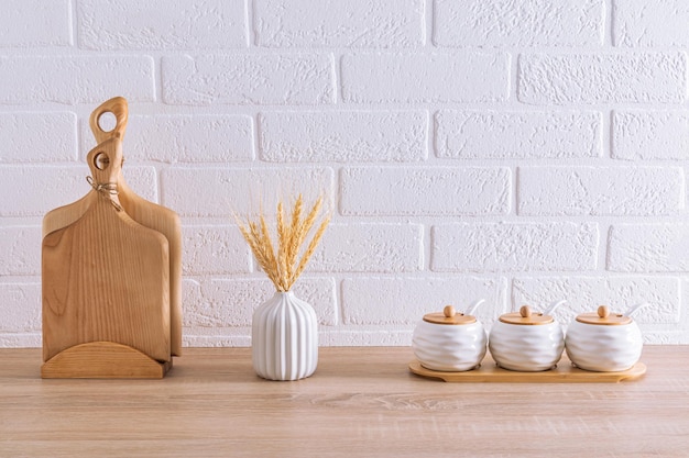 Un ensemble de pots de stockage en céramique blanche et de planches à couper en bois à l'intérieur d'une cuisine écologique minimalisme Éco-articles