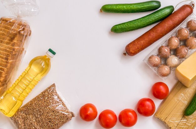 Un ensemble de produits sur fond blanc. Épicerie, légumes, beurre, œufs et saucisses. Paquet alimentaire