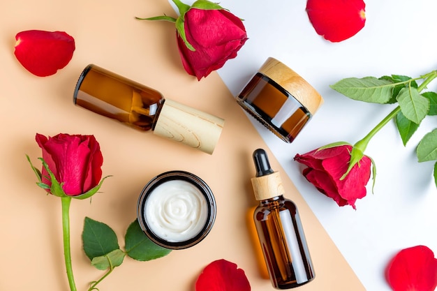 Ensemble de produits de soins de la peau dans des botlles en verre foncé crème sérum fluide masque sur fond beige avec des roses rouges Maquette sans marque