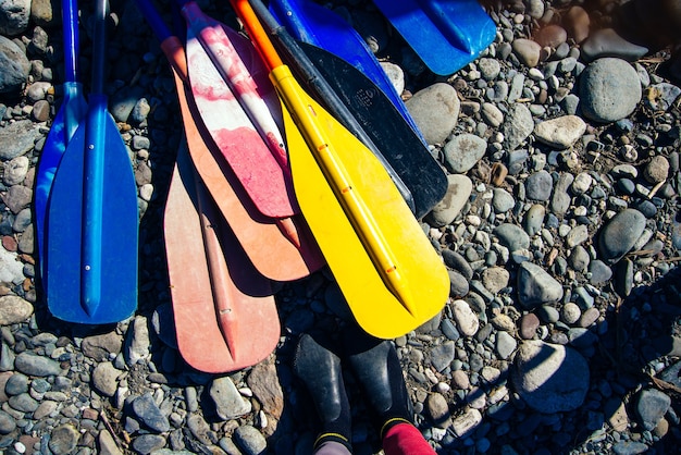 Ensemble de rames colorées et pagaies de kayak et canoë sur les rochers de la plage