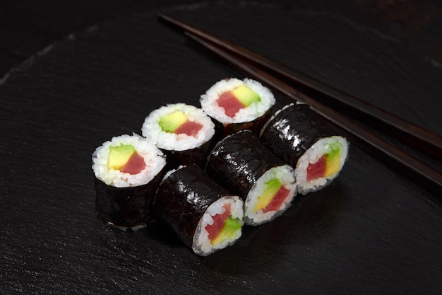 Ensemble De Rouleaux De Sushi Au Thon Et à L'avocat Sur Fond De Bureau Noir