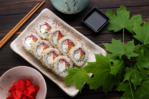 ensemble de rouleaux de sushi avec du riz au fromage à la crème et du saumon sur une planche décorée de gingembre sur un bois