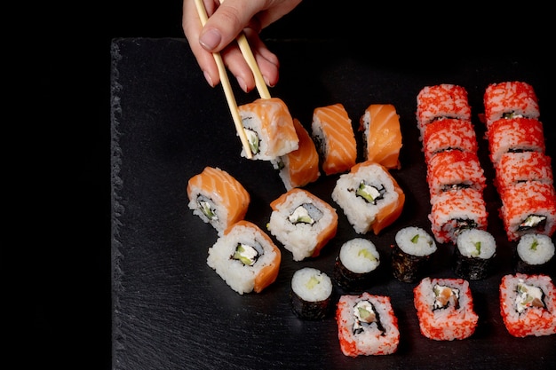 Ensemble de rouleaux de sushi sur fond d'ardoise noire nourriture poisson philadelphie saumon japonais délicieux sushi riz concombre repas traditionnel wasabi frais sain gastronomique cuisine crue