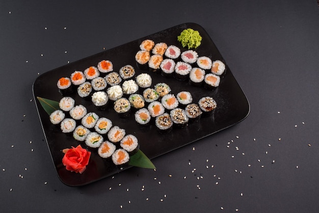 Ensemble de rouleaux de sushi japonais servi sur plaque noire sur fond sombre