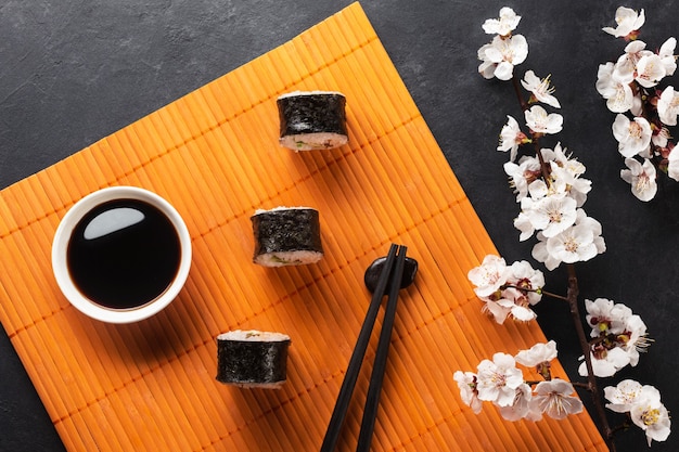 Ensemble de rouleaux de sushi et maki avec branche de fleurs blanches sur table en pierre. Vue de dessus.