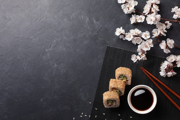 Ensemble de rouleaux de sushi et maki avec branche de fleurs blanches sur table en pierre. Vue de dessus.