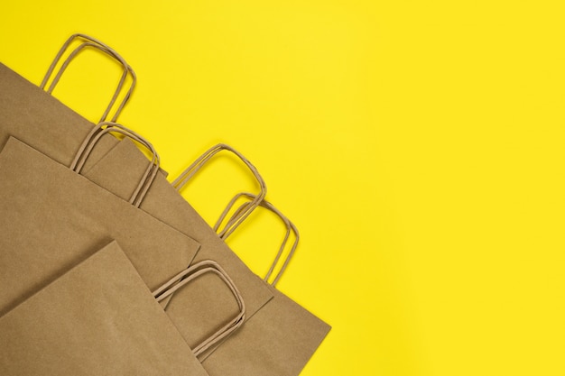 Ensemble de sacs en papier artisanal pour faire du shopping sur une table jaune.