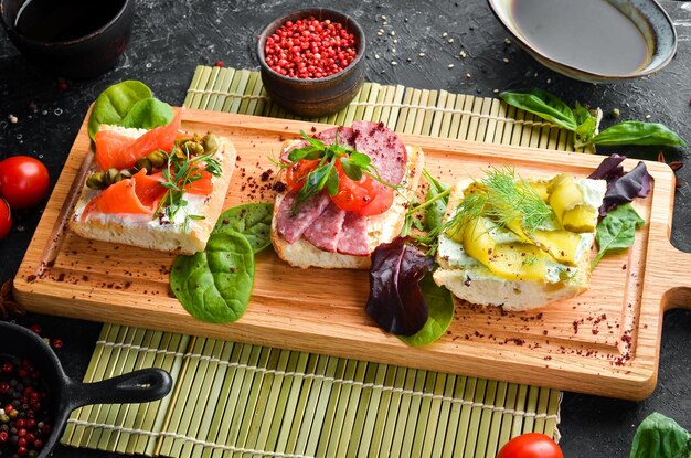 Ensemble de sandwichs aux légumes et au saumon sur une planche de bois Vue de dessus Style rustique