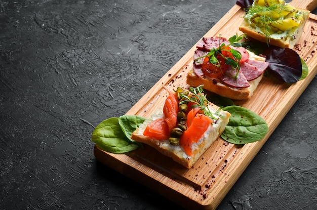 Ensemble de sandwichs aux légumes et au saumon sur une planche de bois Vue de dessus Style rustique