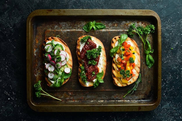 Ensemble de sandwichs maison Bruschetta aux tomates prosciutto légumes et fromage sur fond de pierre noire Vue de dessus