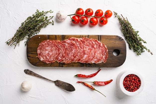 Ensemble de saucisses tranchées Salami Milano, sur fond de table en pierre blanche, vue de dessus à plat