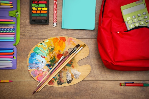 Ensemble scolaire avec palette de sac à dos et fournitures sur fond en bois