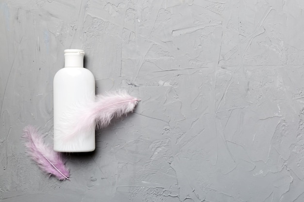 Ensemble de sérums de soins de la peau sur fond pastel rose avec des plumes d'autruche Spa produit cosmétique pot de crème branding maquette vue de dessus avec espace de copie