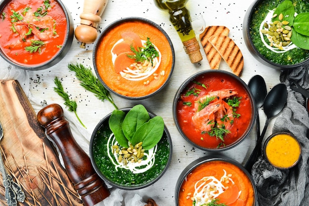 Ensemble de soupes savoureuses colorées sur fond de bois blanc Soupe aux épinards, tomates et carottes Alimentation saine