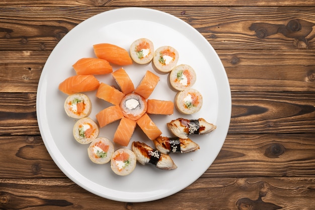 Ensemble de sushi avec maki de Philadelphie, nigiri unagi et saké nigiri sur une plaque en céramique ronde blanche