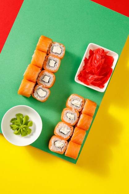 Ensemble de sushis sur fond clair coloré servi avec sauce soja wasabi et gingerxA