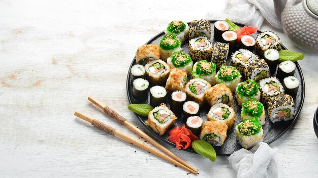 Ensemble de sushis traditionnels sur une plaque noire Sushi et rouleaux sur fond de bois blanc