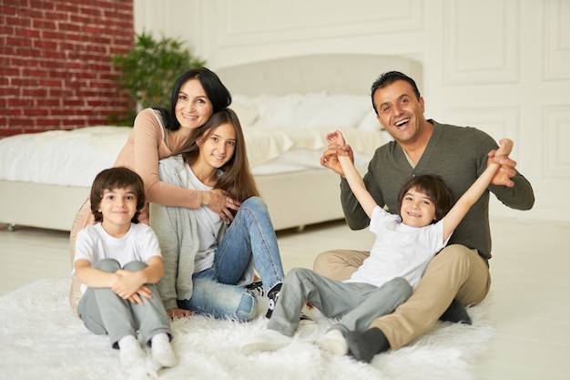 Ensemble tourné sur toute la longueur d'une adolescente de la famille latine joyeuse et de petits garçons jumeaux souriant