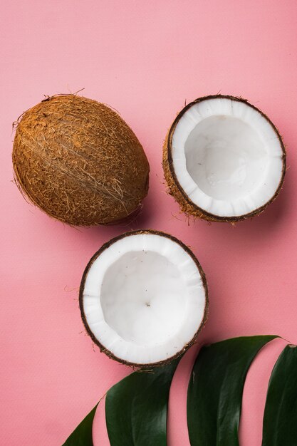 Ensemble de tranches de noix de coco, sur fond d'été texturé rose, vue de dessus à plat