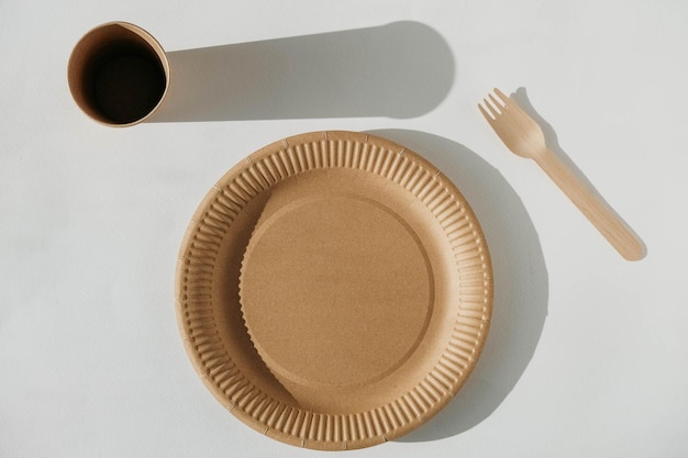 Ensemble de vaisselle jetable tasse assiette en papier kraft et fourchette en bois sur fond blanc