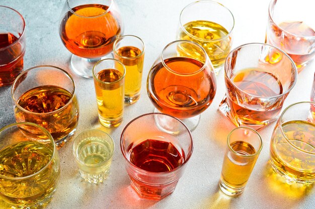 Photo un ensemble de verres avec des boissons alcoolisées fortes whisky brandy cognac ou bourbon et rhum vue latérale boissons alcoolisées fortes sur un fond en béton