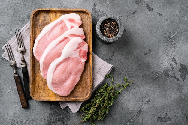 Ensemble de viande de porc crue en tranches, sur fond de table en pierre grise, vue de dessus à plat, avec espace de copie pour le texte