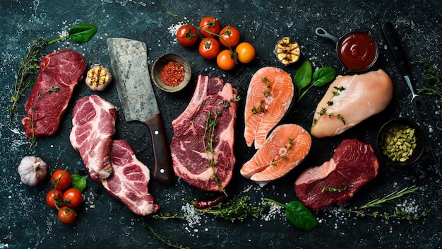 Ensemble de viande Steak de poisson steak de veau et poitrine de poulet Vue de dessus Sur un fond de pierre noire