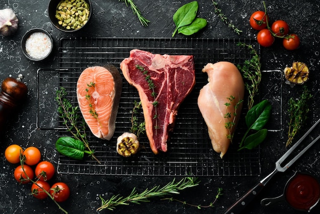 Un ensemble de viandes différentes steak de saumon steak de boeuf et poitrine de poulet Sur un fond de pierre noire