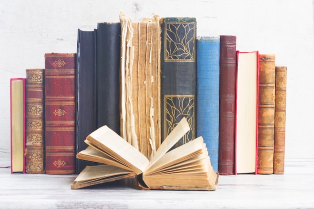 Ensemble de vieux livres avec un ouvert sur bois blanc