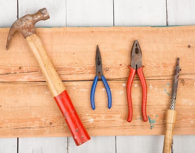 Ensemble de vieux outils marteau pinces et fer à souder sur fond de bois