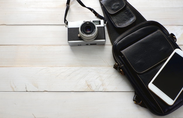 Photo ensemble de voyage avec sac en cuir noir, smartphone et appareil photo vintage