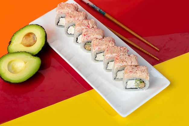 Ensembles de sushi Nigiri Uramaki California Philadelphia sur une assiette blanche Près de gingembre et de wasabi Sauce soja dans un bol blanc Sur un fond coloré