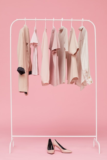 Ensembles de vêtements suspendus sur cintre avec des chaussures sur le sol isolé sur fond rose