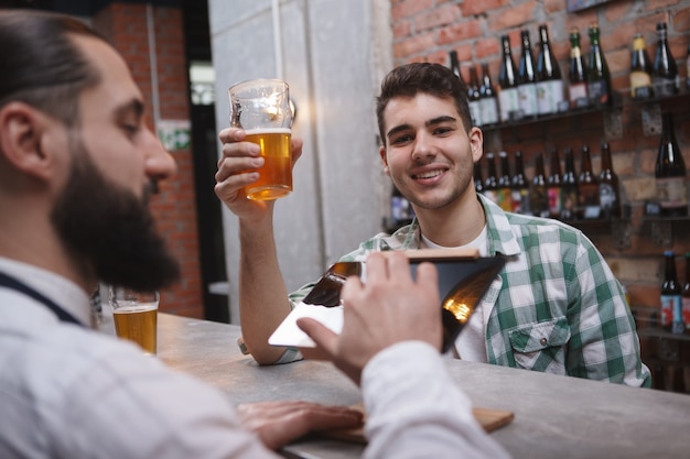 Enthousiaste bel homme grillage avec son verre à bière, buvant au pub