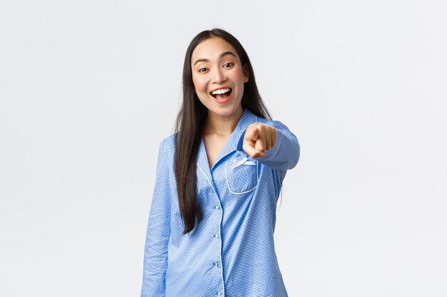 Enthousiaste Belle Fille Asiatique En Pyjama Bleu Pointant Le Doigt à La Caméra Et Souriant Heureux